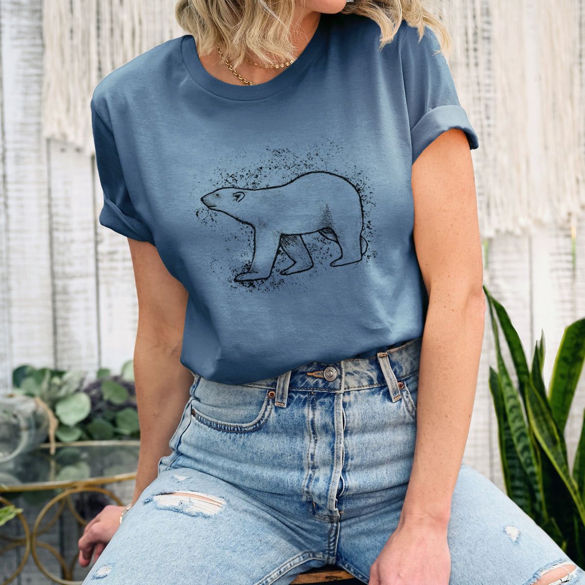 Woman wearing a steel blue lightweight cotton t-shirt printed with a black ink illustration of a polar bear walking across snow.
