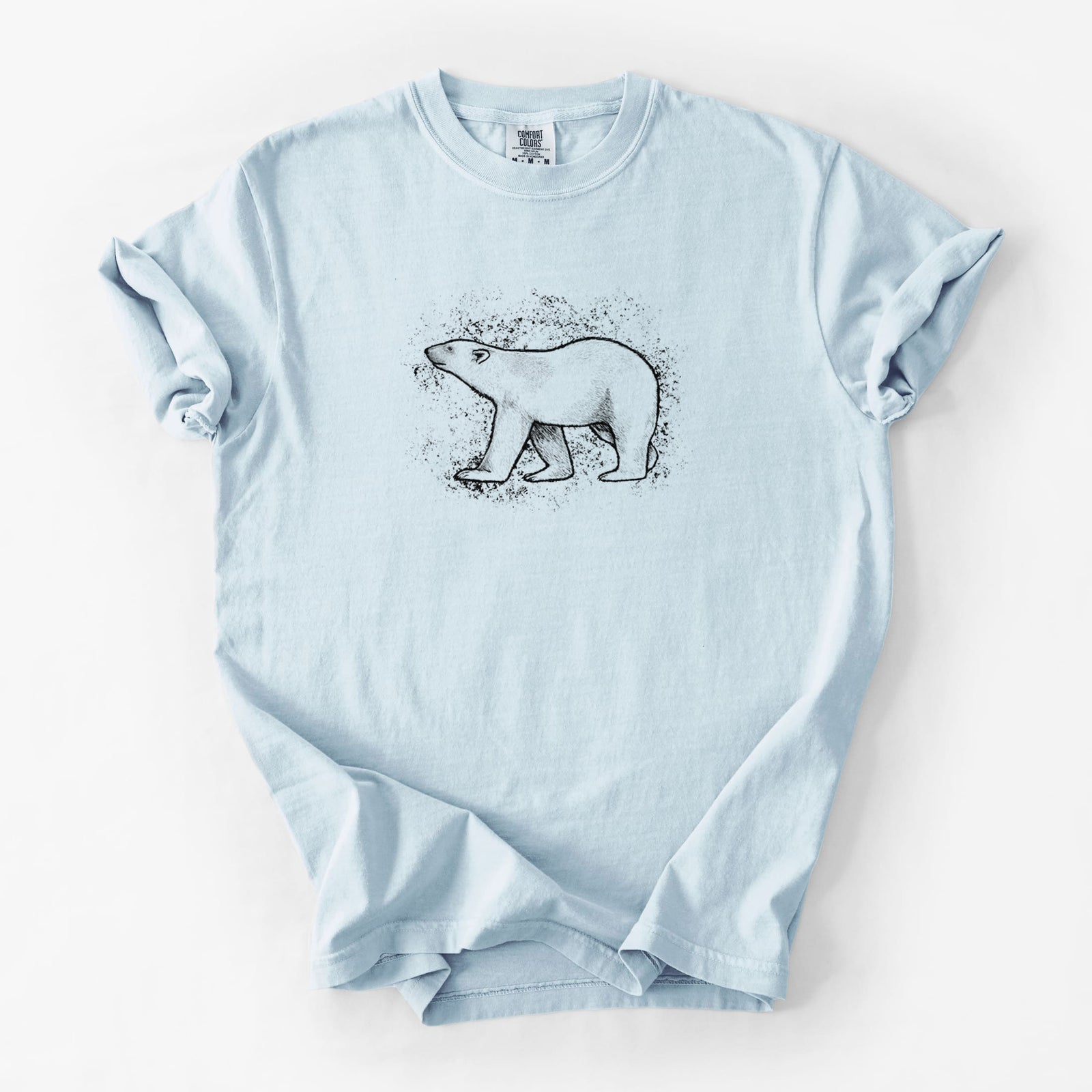 Blue jean Comfort Colors t-shirt laid flat, printed with a black ink illustration of a polar bear walking across snow.