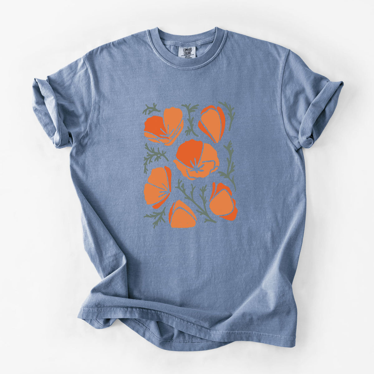 Blue jean Comfort Colors t-shirt laid flat, printed with a full-color illustration of orange California poppies with blue-green leaves.