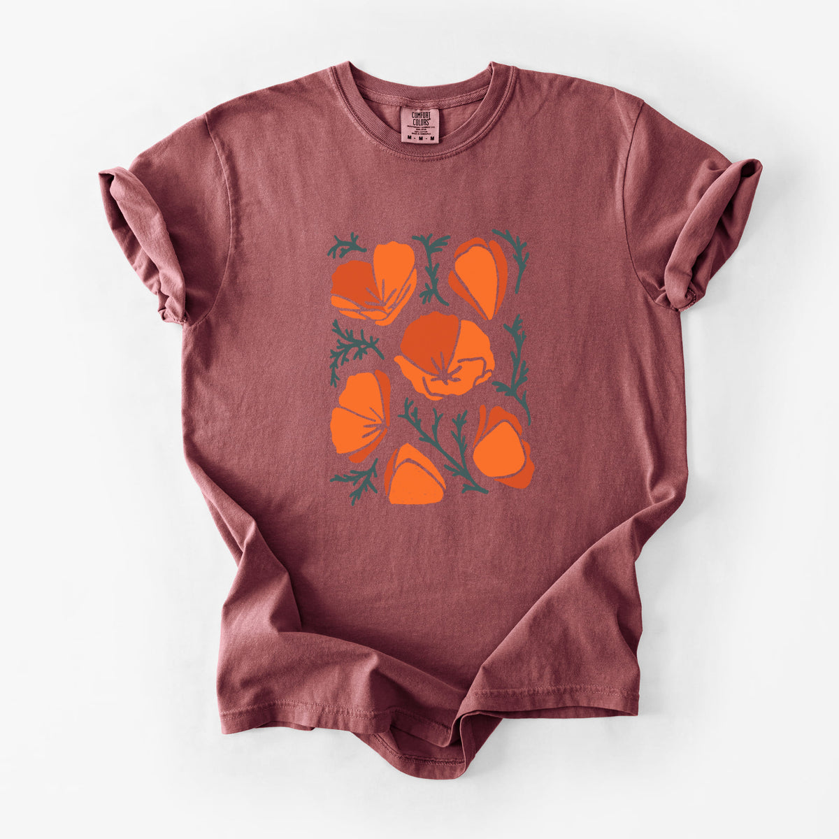 Brick red Comfort Colors t-shirt laid flat, printed with a full-color illustration of orange California poppies with blue-green leaves.