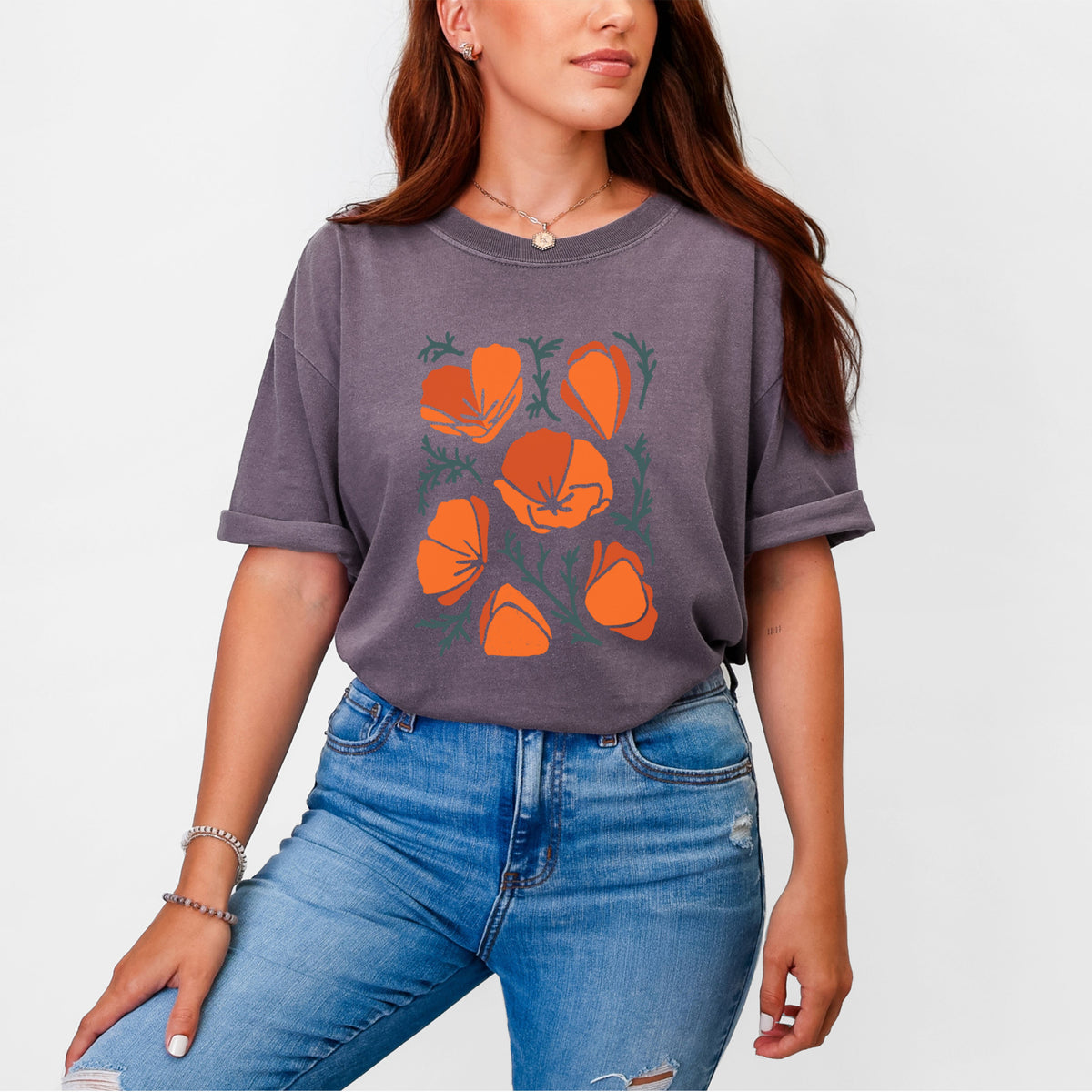 Woman wearing a Comfort Colors t-shirt printed with a full-color illustration of orange California poppies with blue-green leaves.