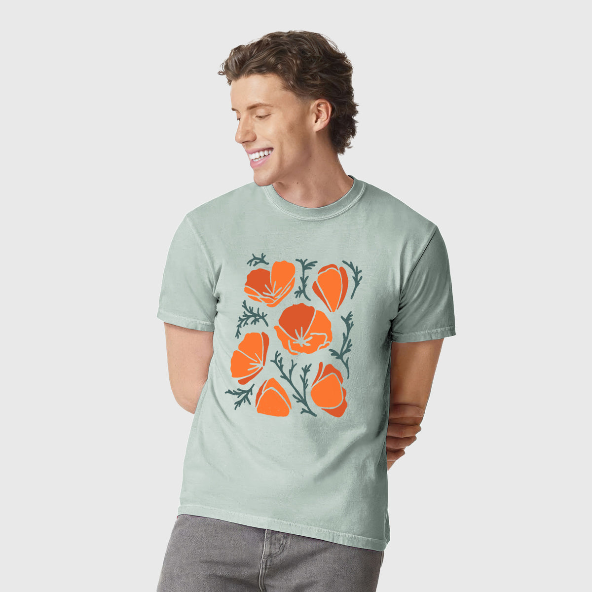 Man wearing a Comfort Colors t-shirt printed with a full-color illustration of orange California poppies with blue-green leaves.