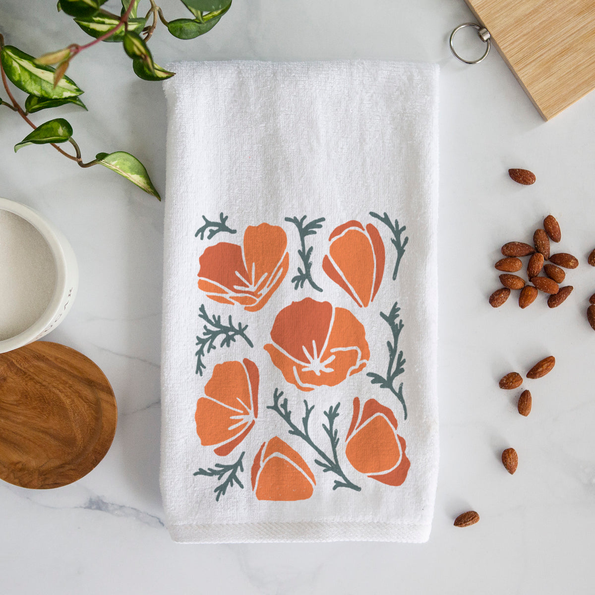 White hand towel printed with a full-color illustration of orange California poppies with blue-green leaves.