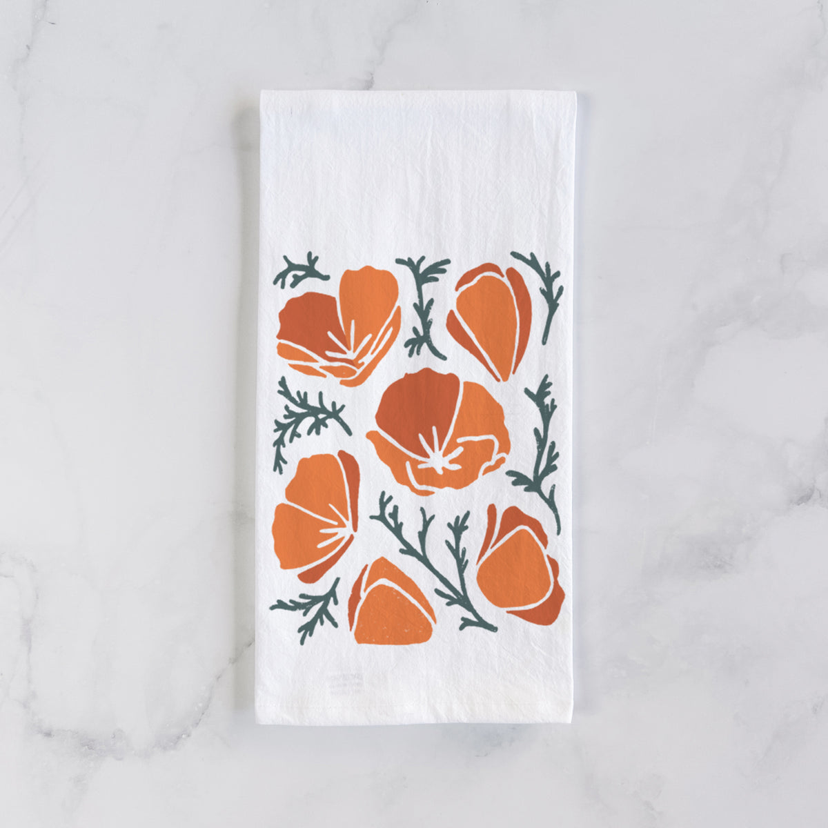 White cotton tea towel laid flat on marble, printed with a full-color illustration of orange California poppies with blue-green leaves.
