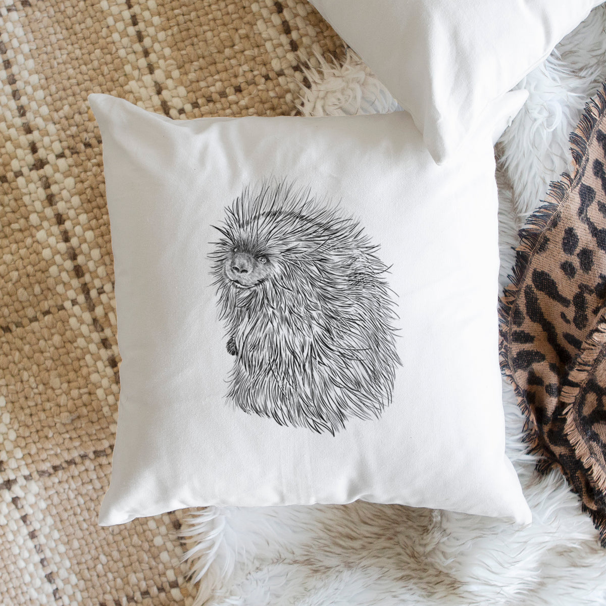 White pillow cover printed with a detailed black ink illustration of a porcupine with its quills raised, on a woven chair.