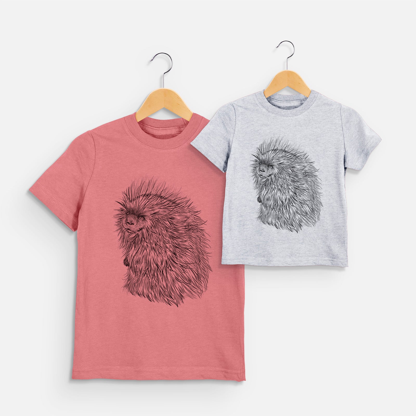 Two youth t-shirts in different colors on hangers, printed with a detailed black ink illustration of a porcupine with its quills raised.