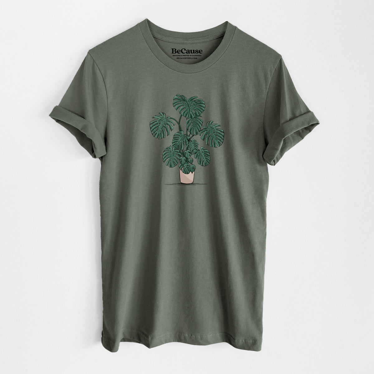 Military green lightweight cotton t-shirt laid flat, printed with a full-color illustration of a large potted Monstera plant.