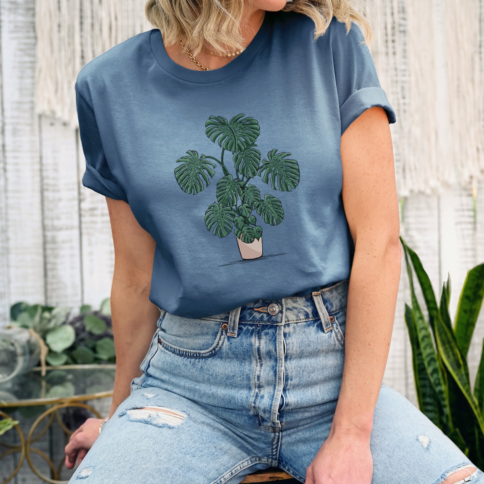Autumn lightweight cotton t-shirt laid flat, printed with a full-color illustration of a large potted Monstera plant.