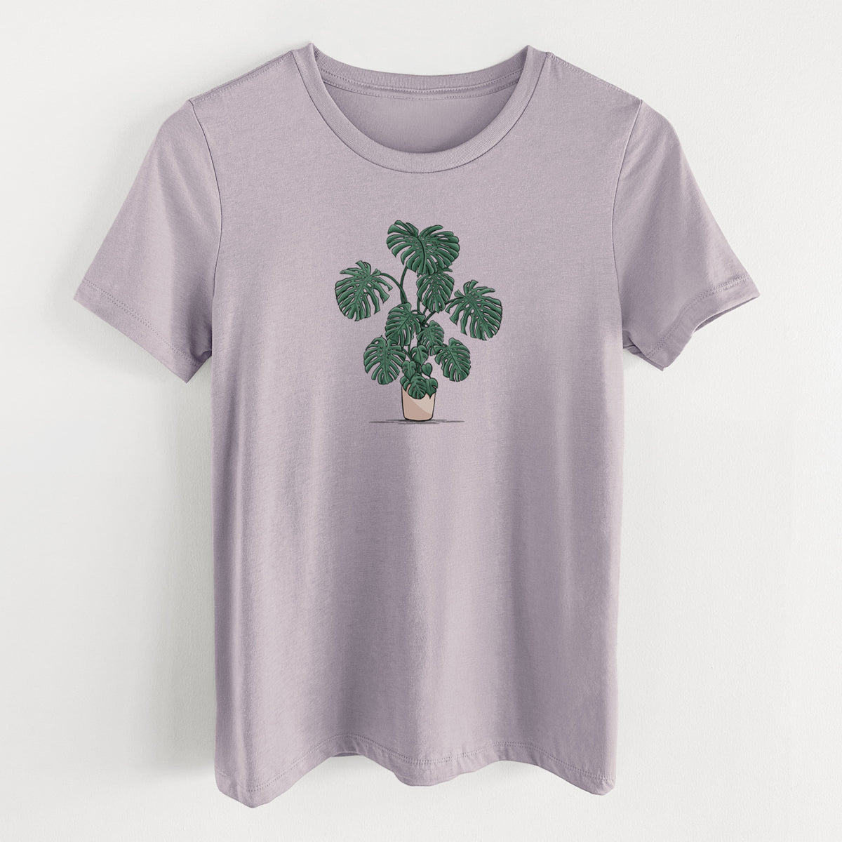 Light violet women's relaxed fit cotton t-shirt laid flat, printed with a full-color illustration of a large potted Monstera plant.