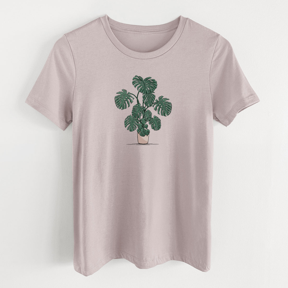 Pink gravel women's relaxed fit cotton t-shirt laid flat, printed with a full-color illustration of a large potted Monstera plant.