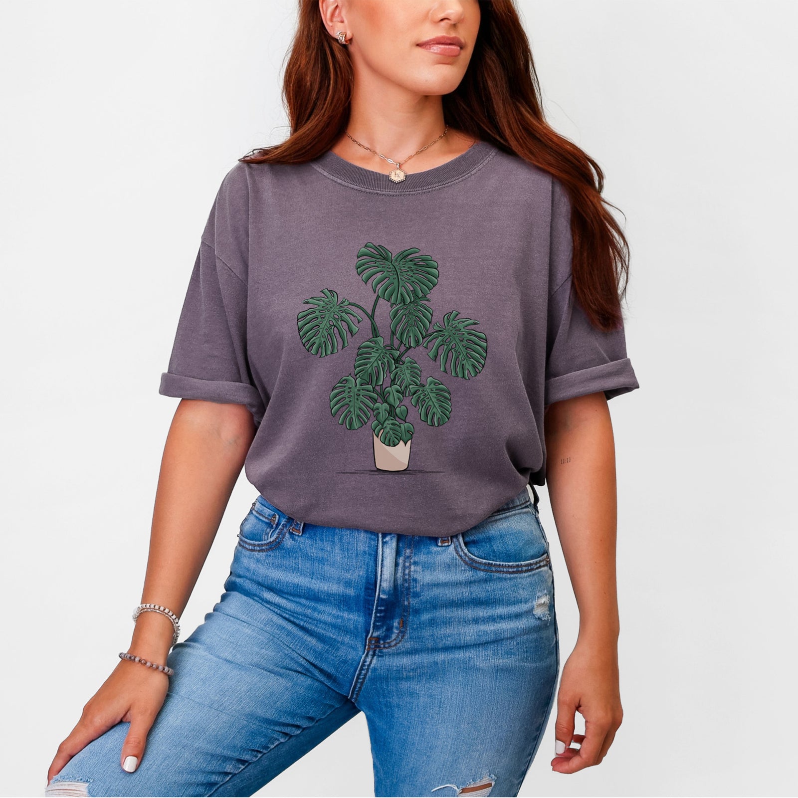 Blue jean Comfort Colors t-shirt laid flat, printed with a full-color illustration of a large potted Monstera plant.