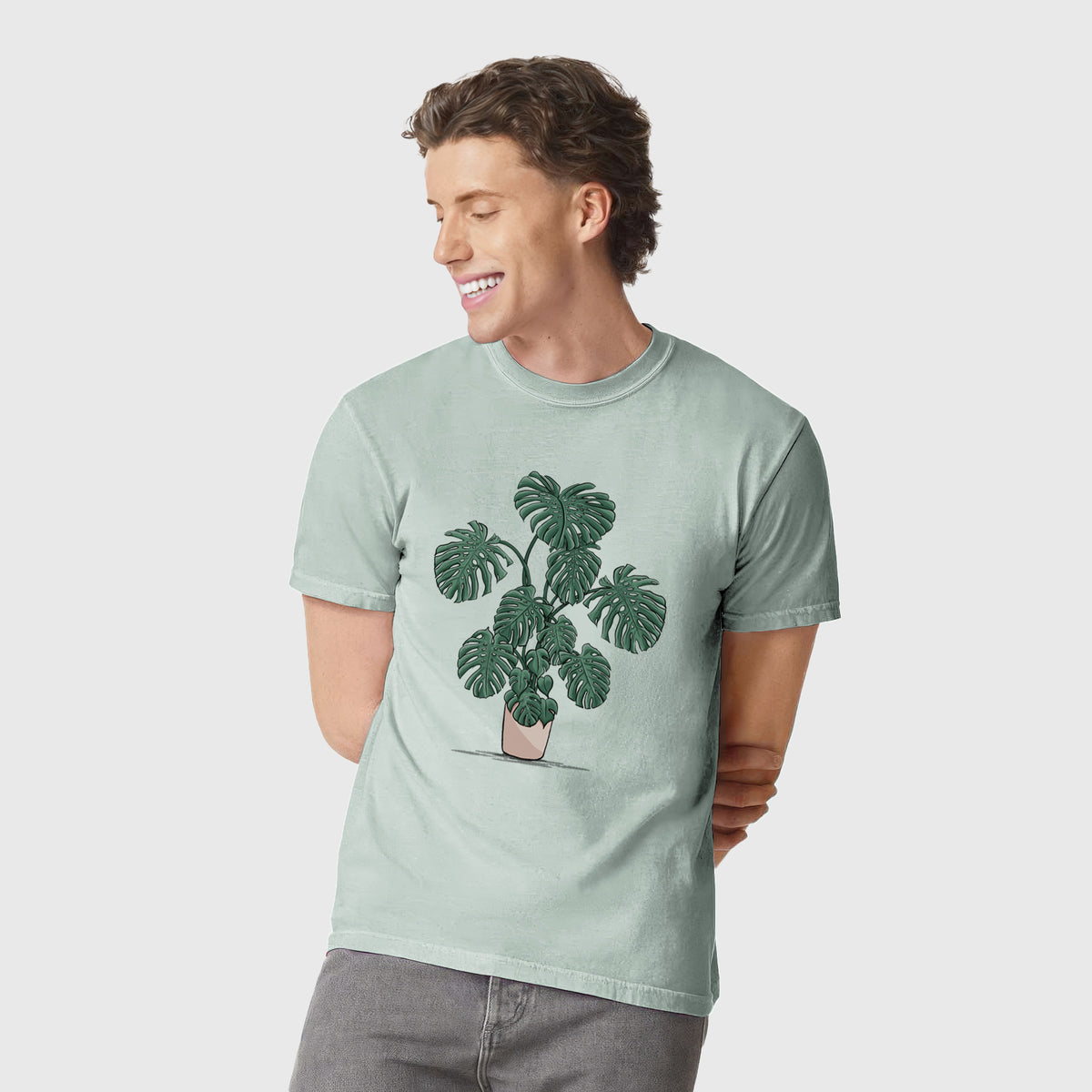 Man wearing a Comfort Colors t-shirt printed with a full-color illustration of a large potted Monstera plant.