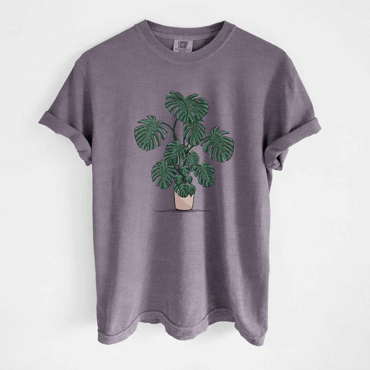 Wine red Comfort Colors t-shirt laid flat, printed with a full-color illustration of a large potted Monstera plant.