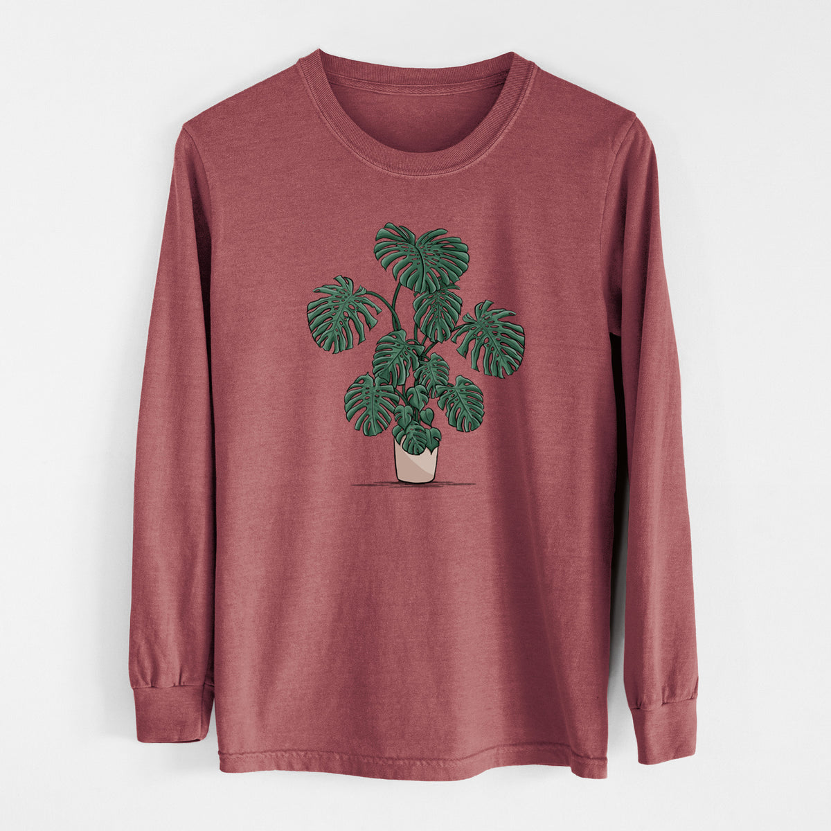 Brick red Comfort Colors long sleeve shirt laid flat, printed with a full-color illustration of a large potted Monstera plant.