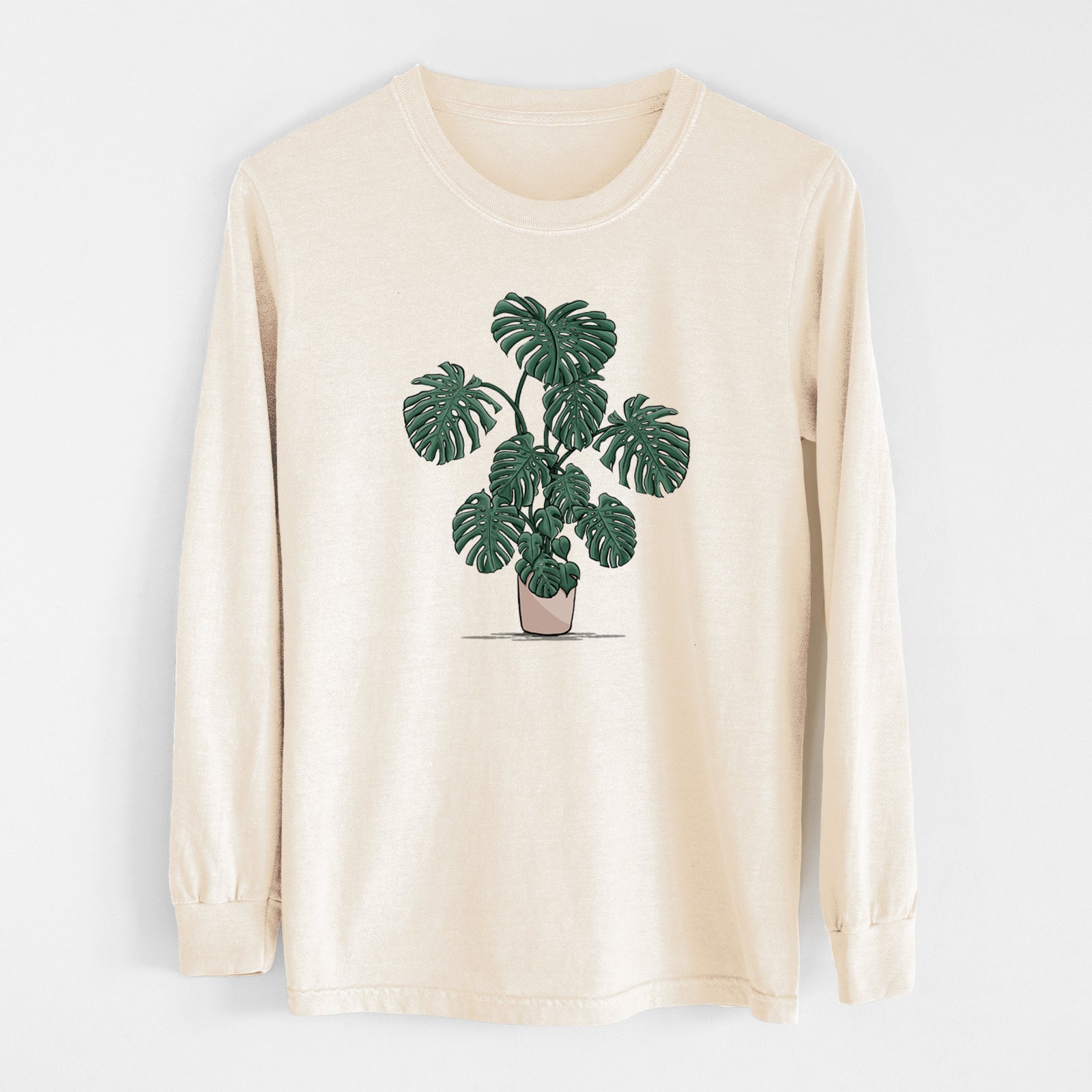 Ivory Comfort Colors long sleeve shirt laid flat, printed with a full-color illustration of a large potted Monstera plant.