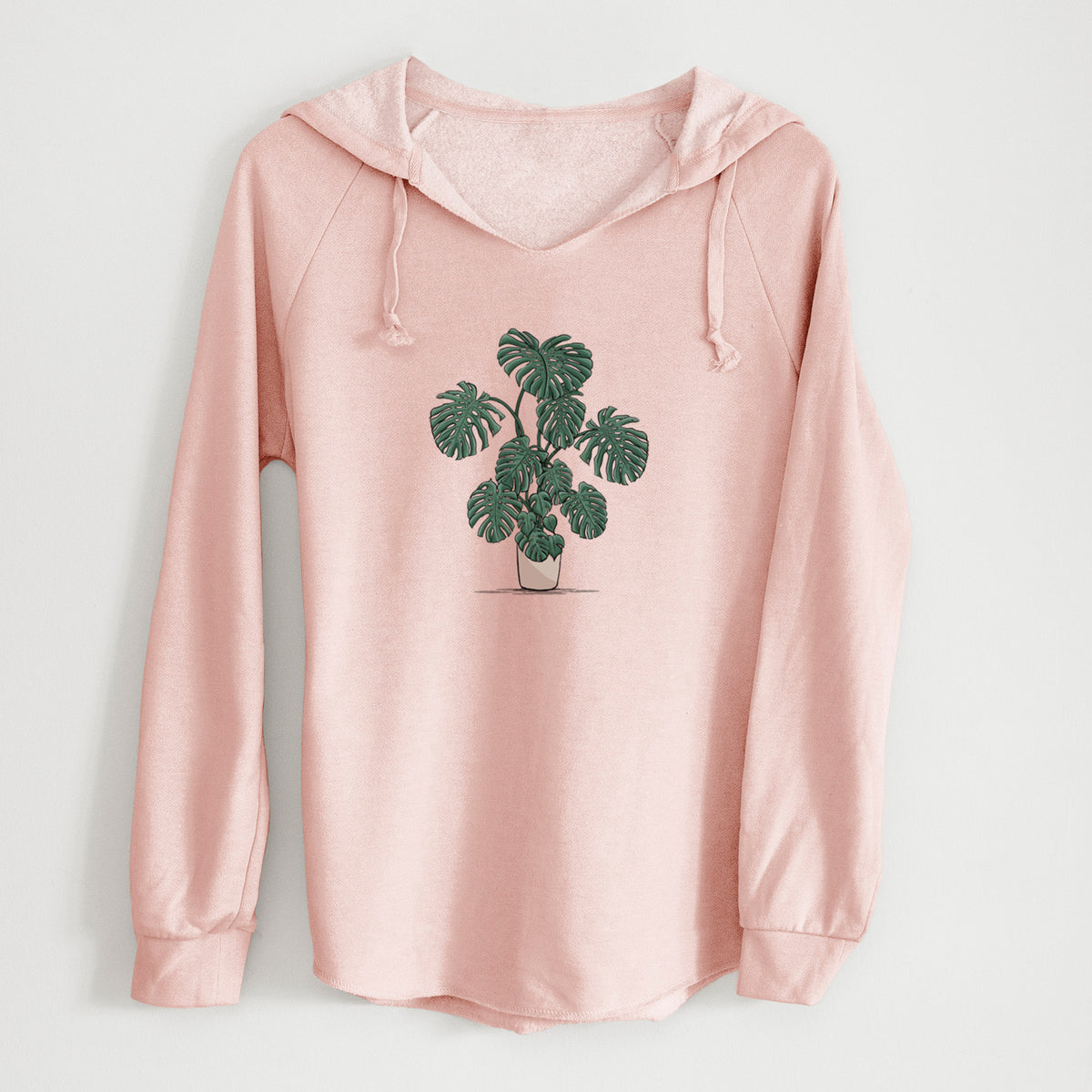 Blush pink women's Cali Wave hooded sweatshirt laid flat, printed with a full-color illustration of a large potted Monstera plant.