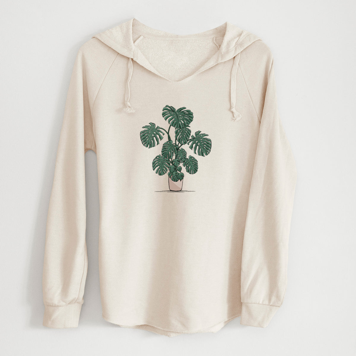 Bone cream women's Cali Wave hooded sweatshirt laid flat, printed with a full-color illustration of a large potted Monstera plant.