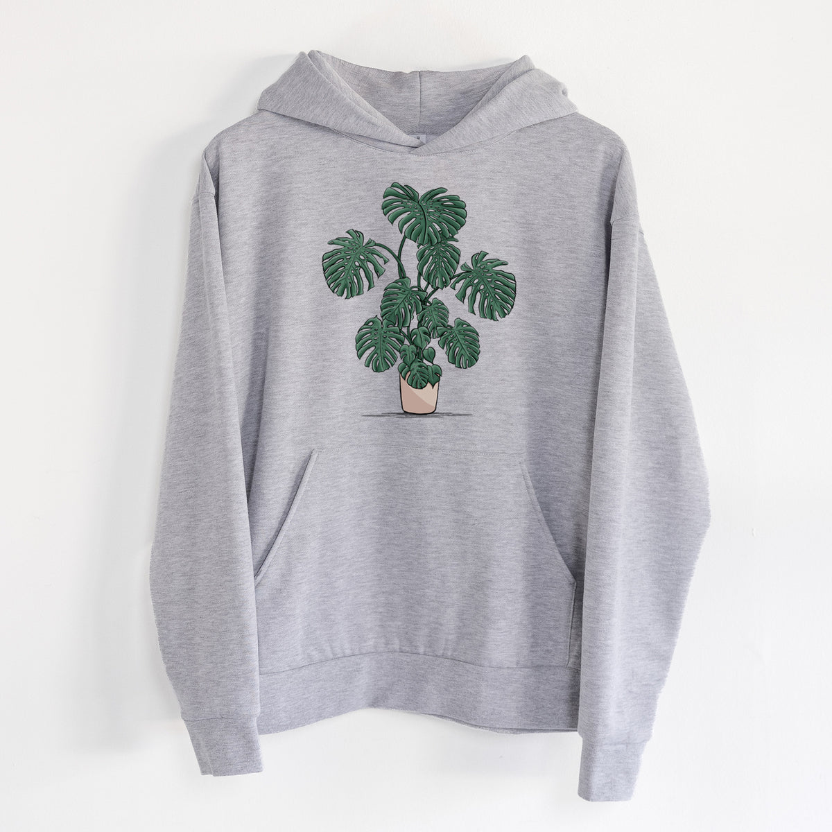 Potted Monstera Plant - Statement Midweight Hoodie in Heather Grey, hanging on a white wall, with a front kangaroo pocket and no drawcords.