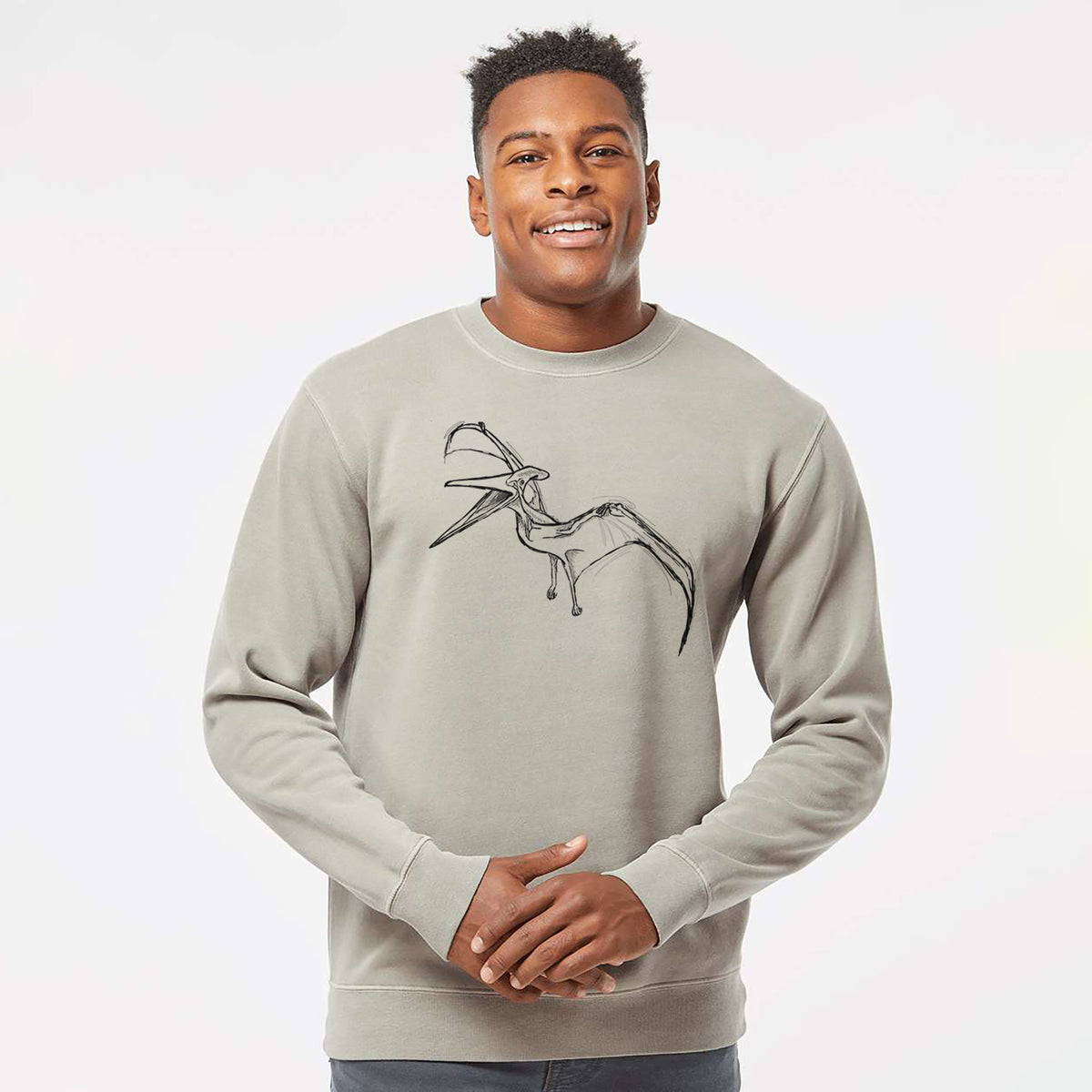Model wearing a cement grey pigment dyed crewneck sweatshirt printed with a black ink illustration of a Pteranodon in flight.