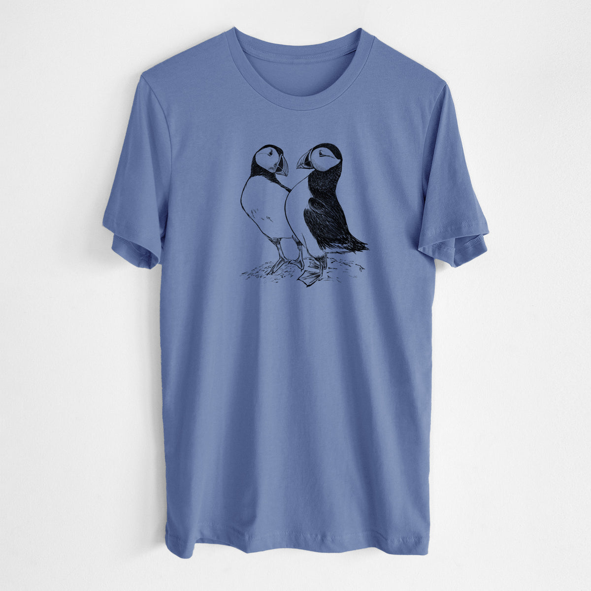 Blue bell lightweight cotton t-shirt laid flat, printed with a detailed black ink illustration of two Atlantic puffins standing side by side.