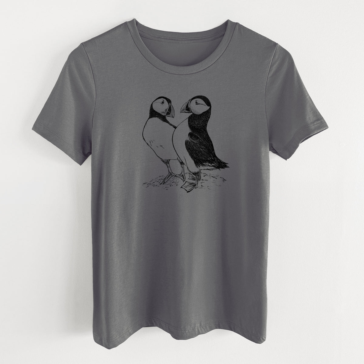 Asphalt women's relaxed fit cotton t-shirt laid flat, printed with a detailed black ink illustration of two Atlantic puffins standing side by side.