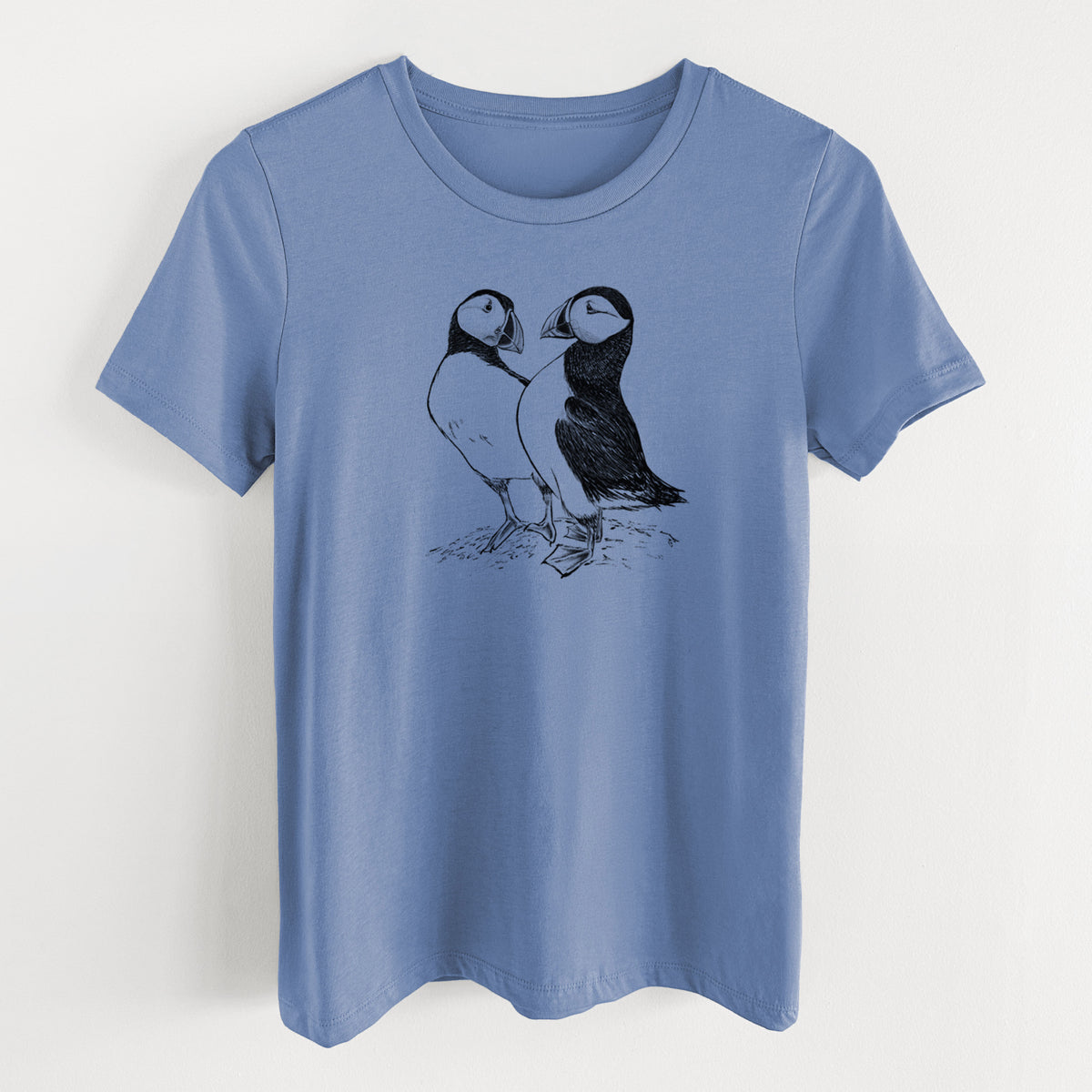 Blue bell women's relaxed fit cotton t-shirt laid flat, printed with a detailed black ink illustration of two Atlantic puffins standing side by side.