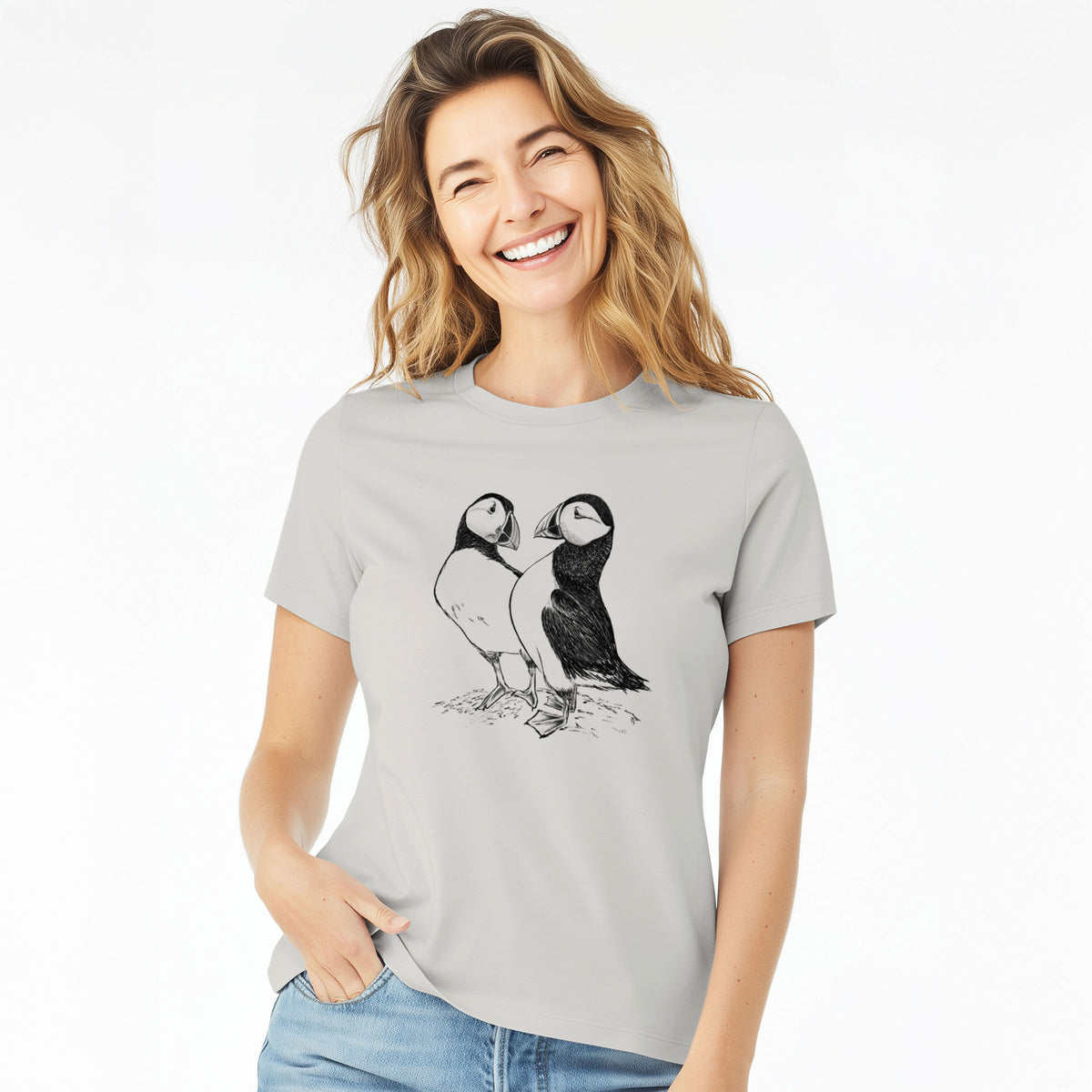 Woman wearing a lunar grey women's relaxed fit cotton t-shirt printed with a detailed black ink illustration of two Atlantic puffins standing side by side.