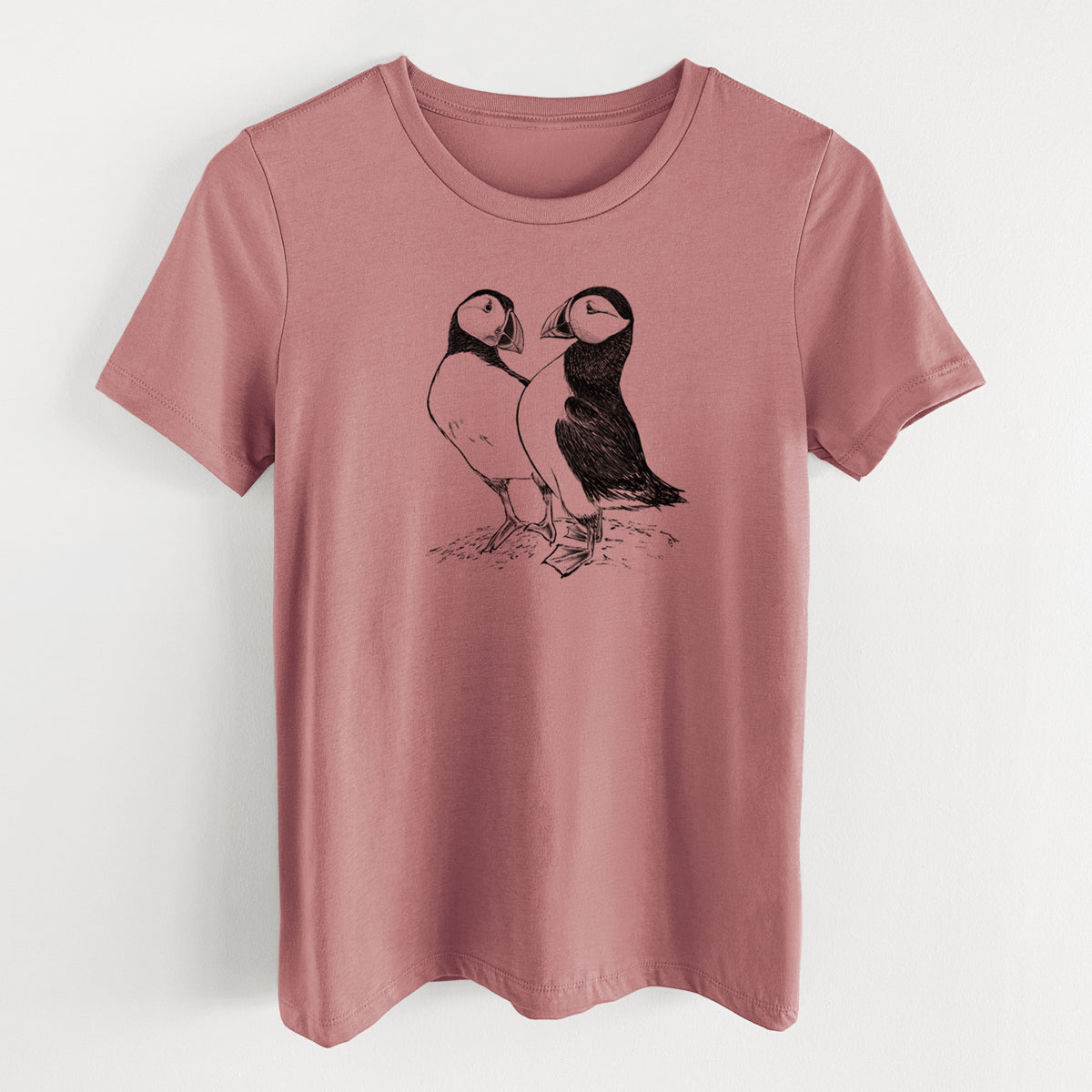Mauve pink women's relaxed fit cotton t-shirt laid flat, printed with a detailed black ink illustration of two Atlantic puffins standing side by side.