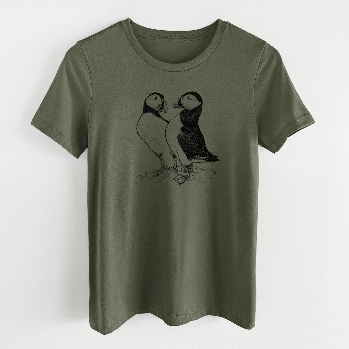 Military green women's relaxed fit cotton t-shirt laid flat, printed with a detailed black ink illustration of two Atlantic puffins standing side by side.