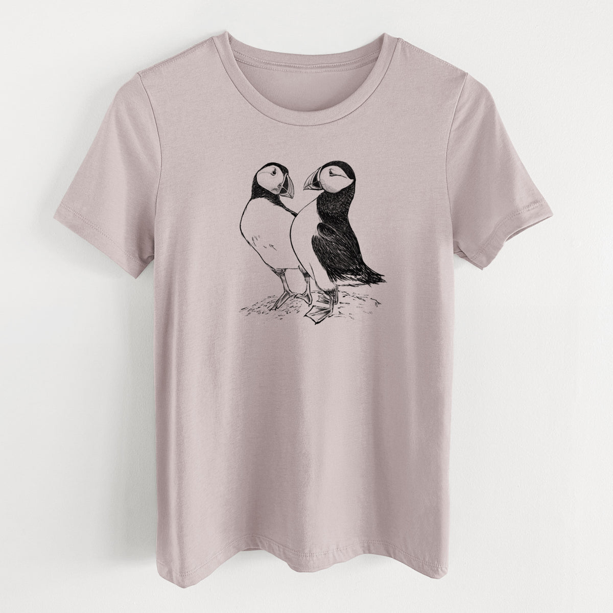 Pink gravel women's relaxed fit cotton t-shirt laid flat, printed with a detailed black ink illustration of two Atlantic puffins standing side by side.