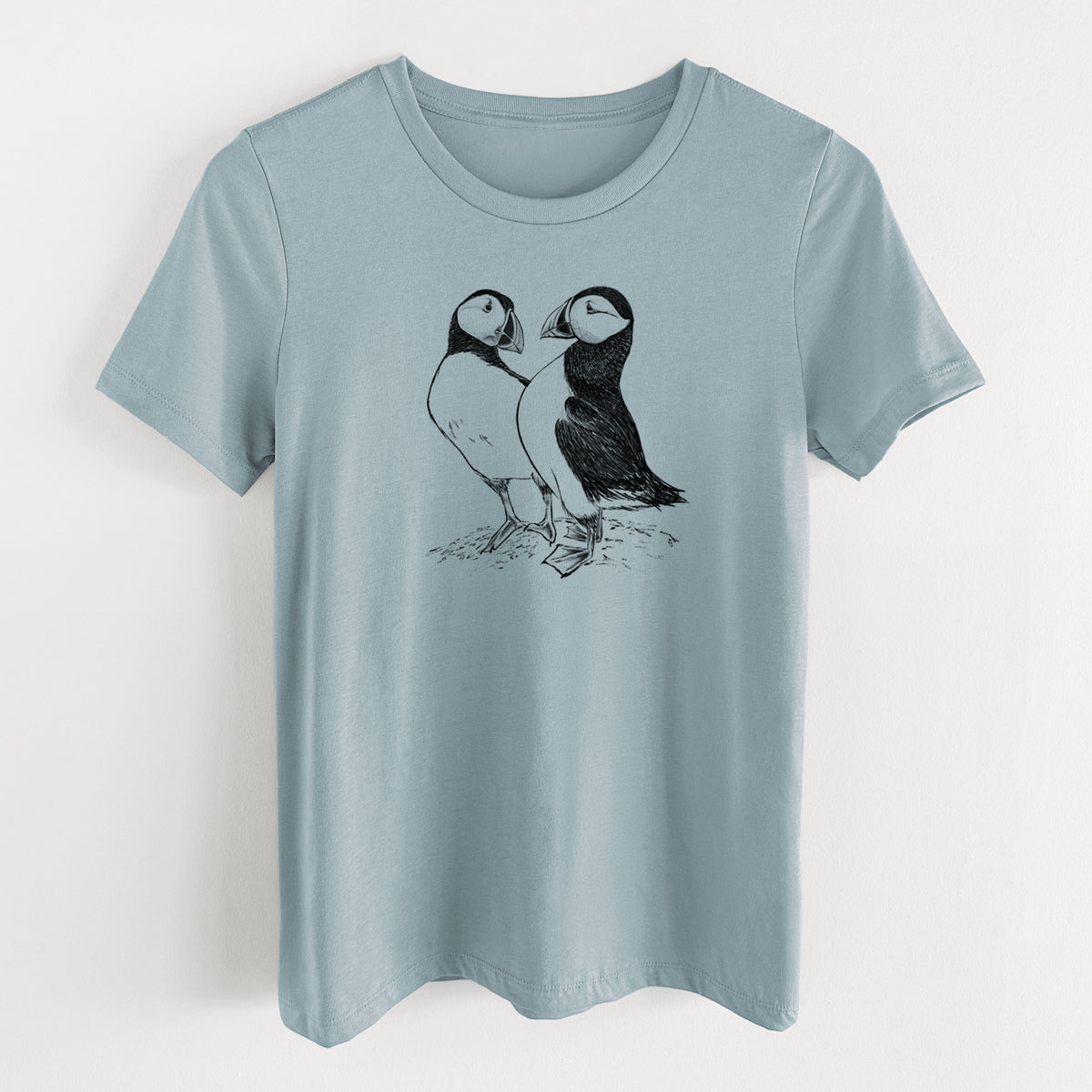 Vintage denim women's relaxed fit cotton t-shirt laid flat, printed with a detailed black ink illustration of two Atlantic puffins standing side by side.