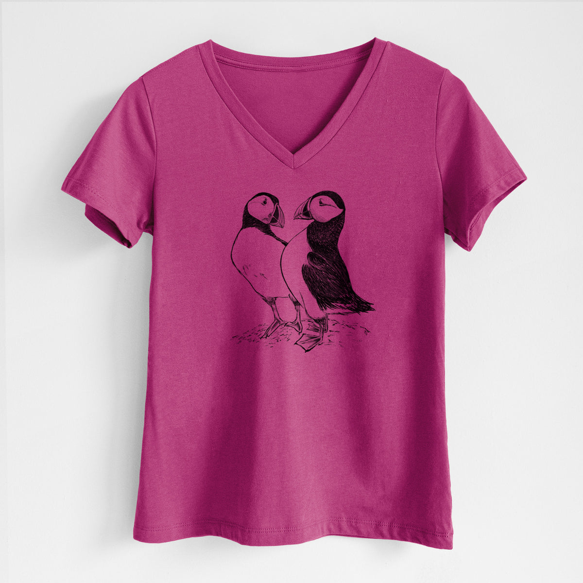 Berry pink women's relaxed fit cotton V-neck t-shirt laid flat, printed with a detailed black ink illustration of two Atlantic puffins standing side by side.