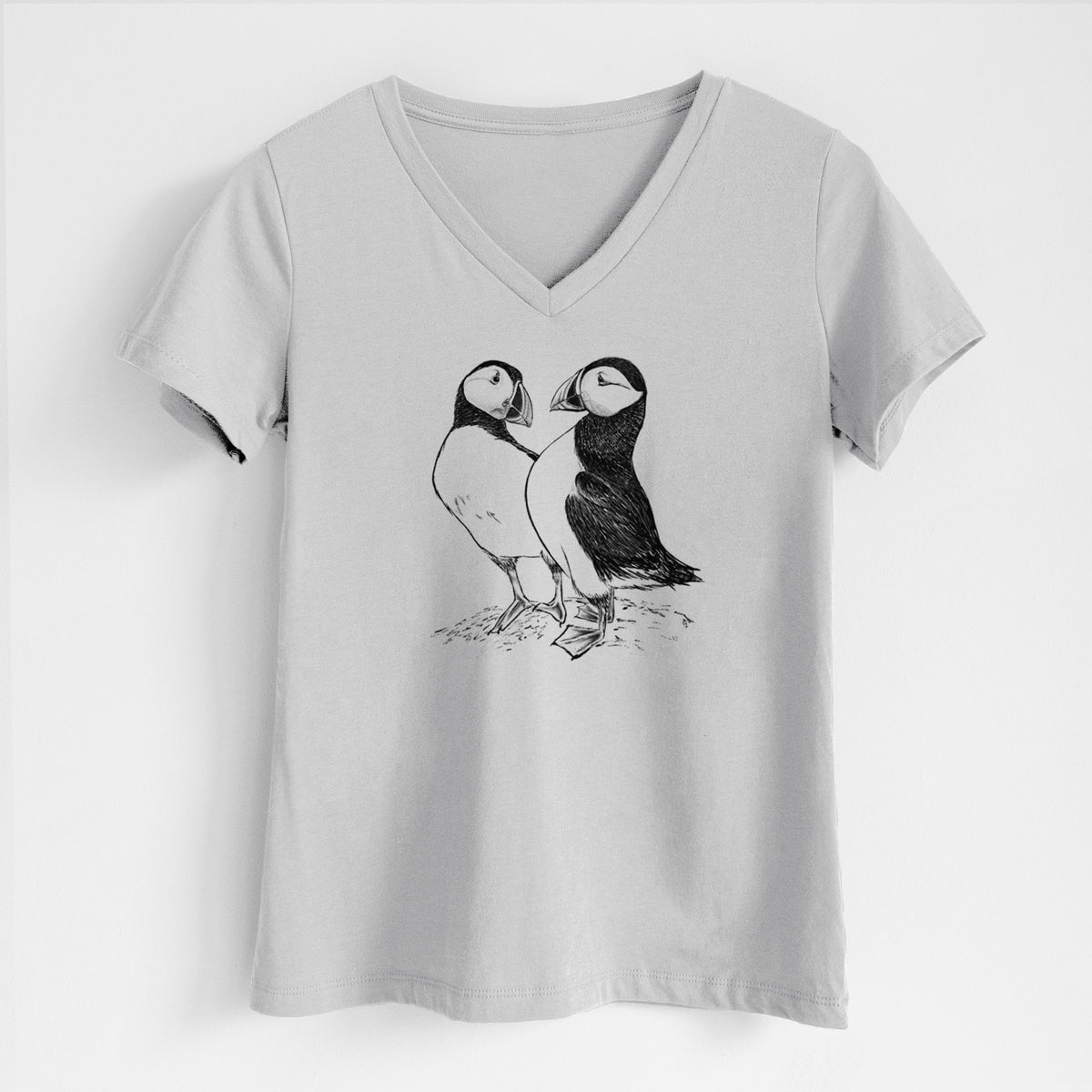 Lunar grey women's relaxed fit cotton V-neck t-shirt laid flat, printed with a detailed black ink illustration of two Atlantic puffins standing side by side.
