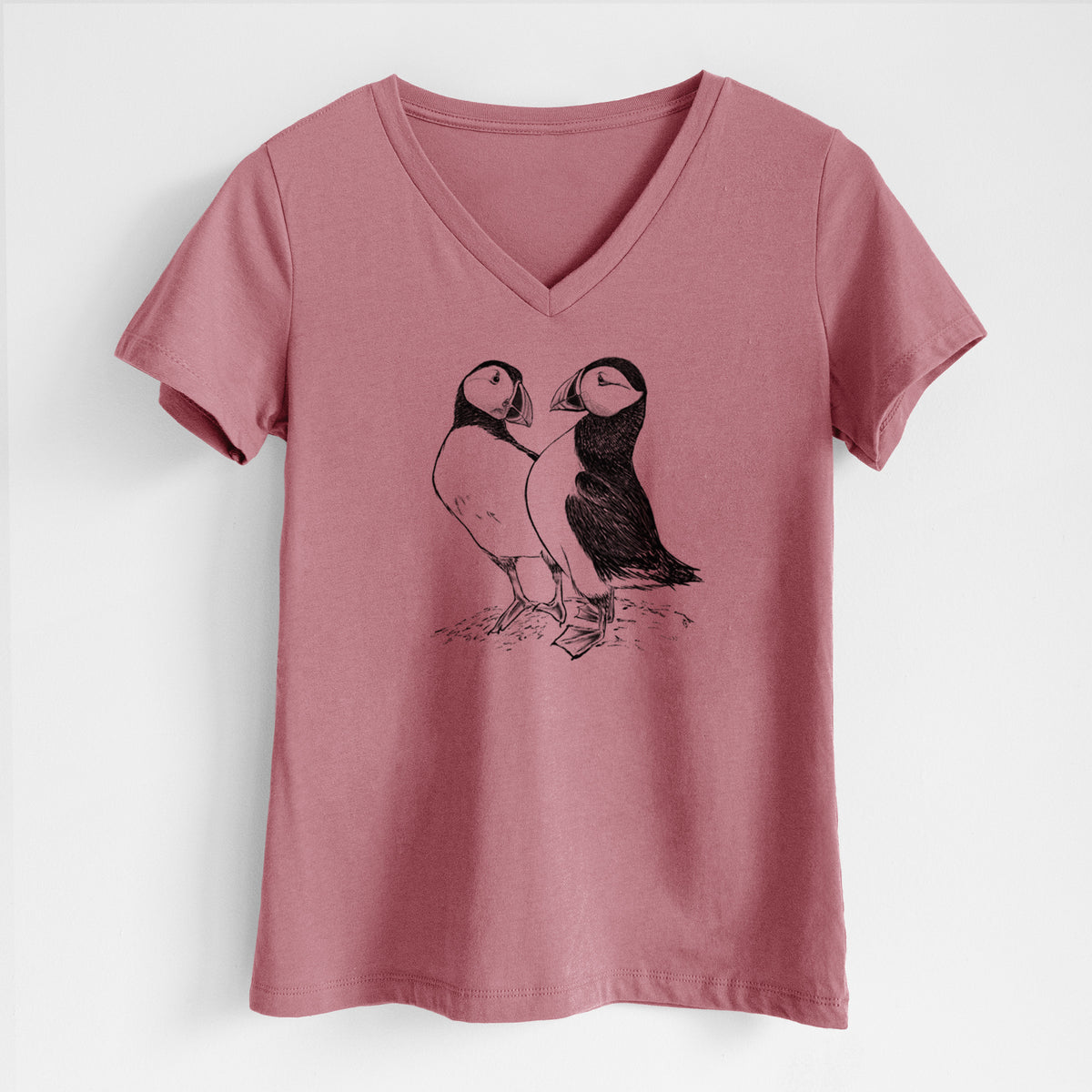 Mauve pink women's relaxed fit cotton V-neck t-shirt laid flat, printed with a detailed black ink illustration of two Atlantic puffins standing side by side.