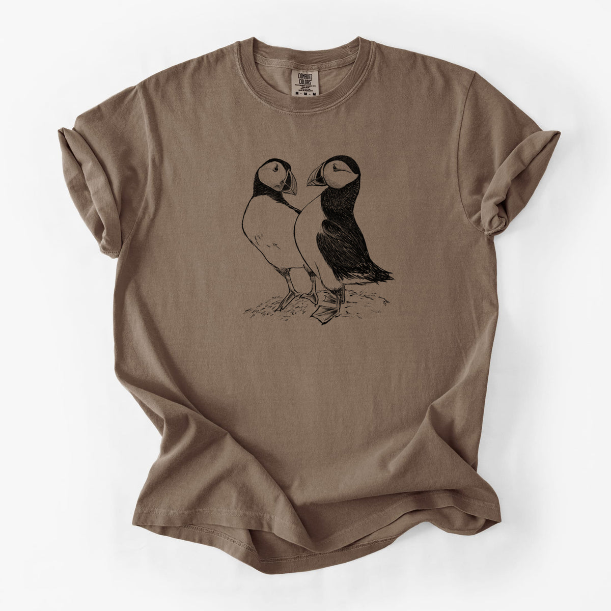 Espresso brown Comfort Colors t-shirt laid flat, printed with a detailed black ink illustration of two Atlantic puffins standing side by side.