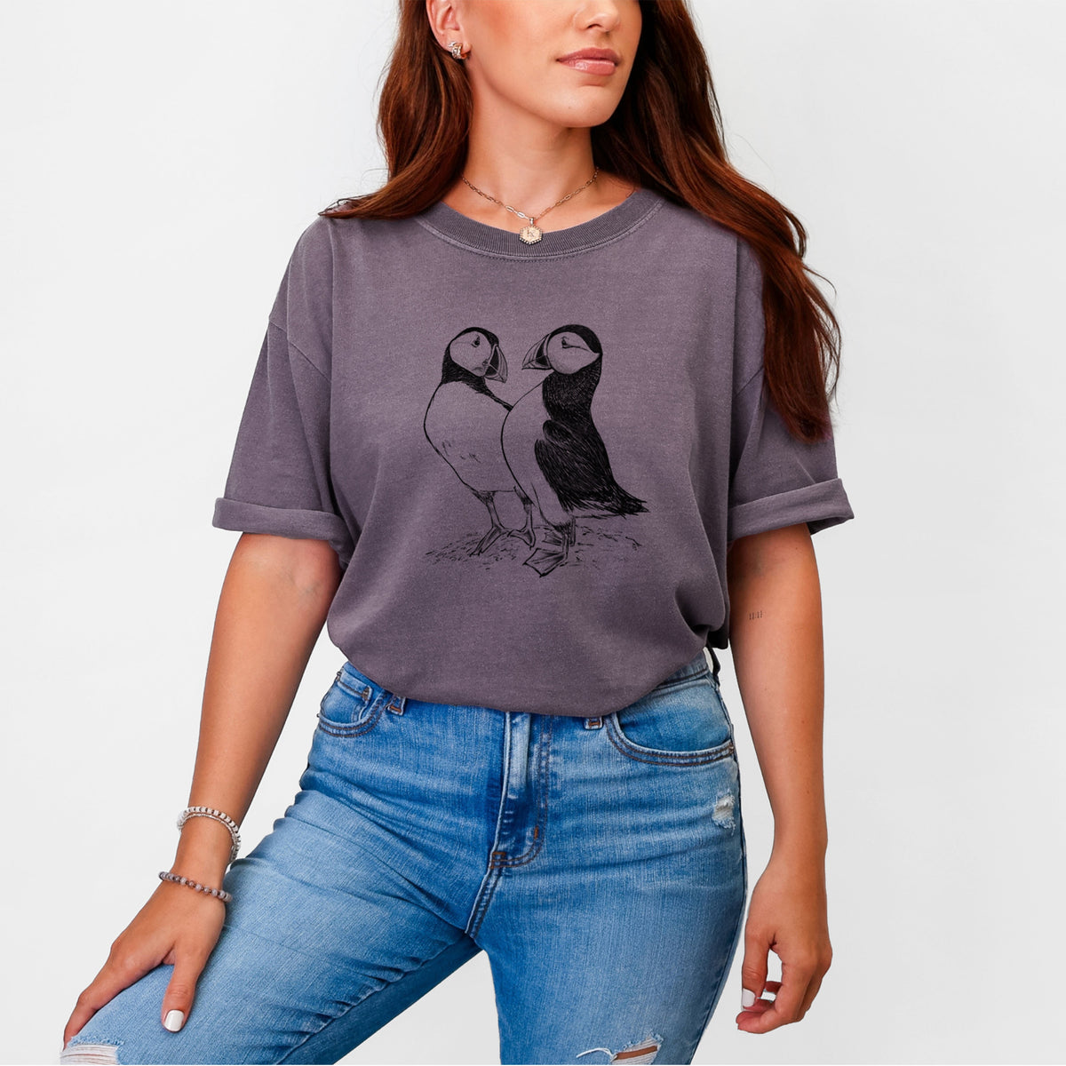 Woman wearing a Comfort Colors t-shirt printed with a detailed black ink illustration of two Atlantic puffins standing side by side.