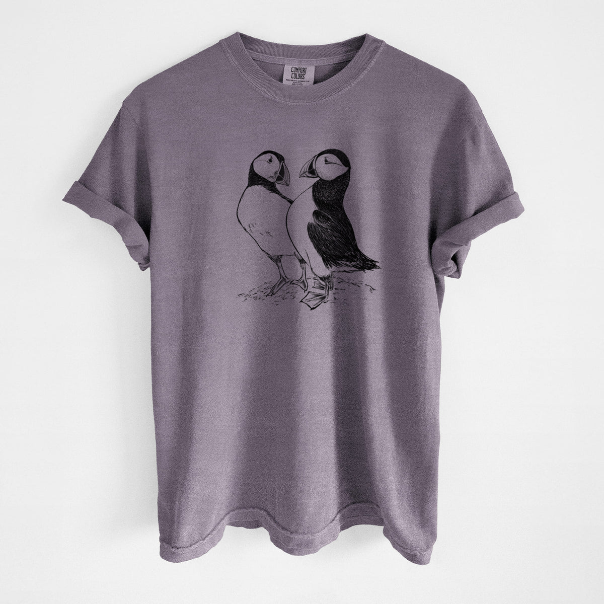 Wine red Comfort Colors t-shirt laid flat, printed with a detailed black ink illustration of two Atlantic puffins standing side by side.