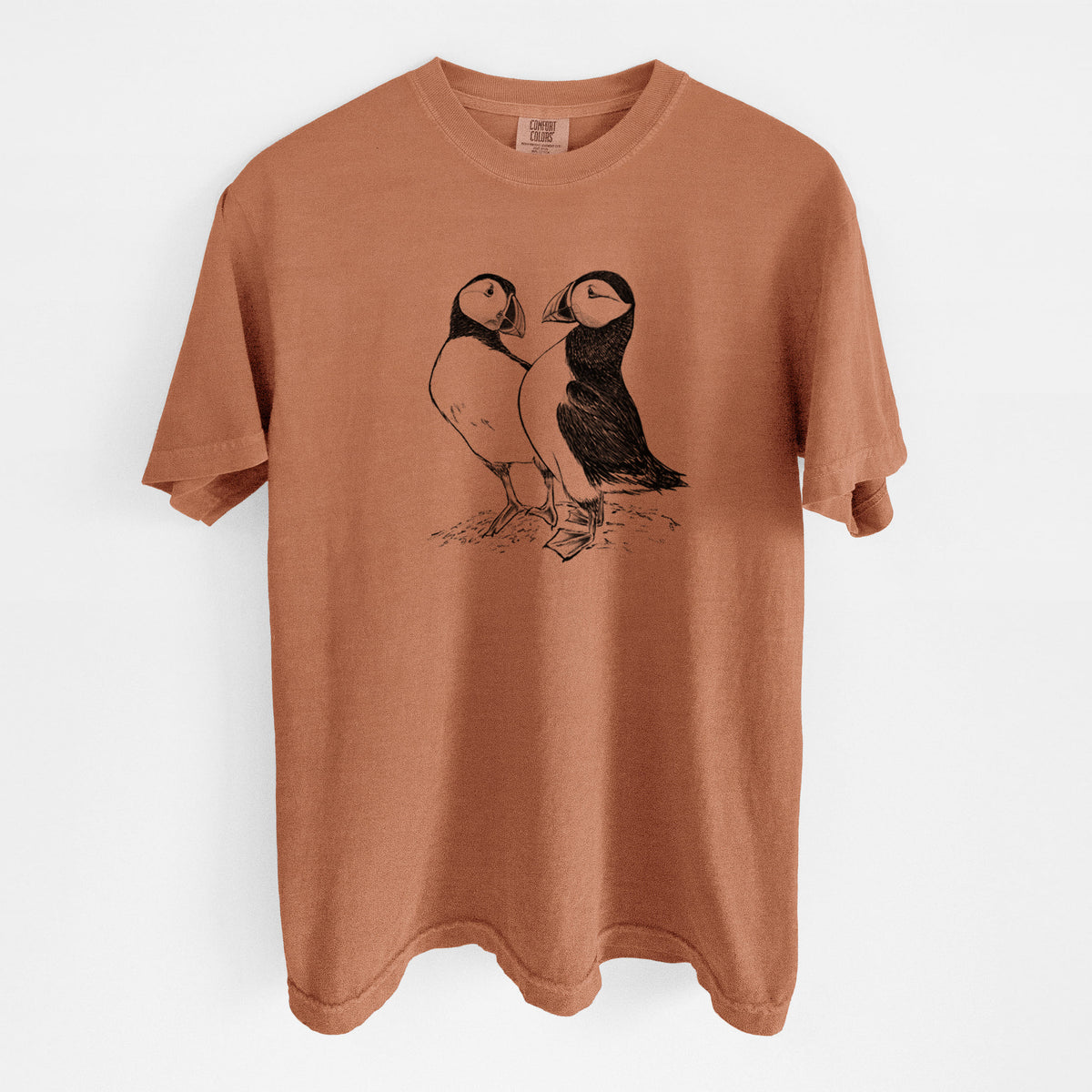 Yam burnt orange Comfort Colors t-shirt laid flat, printed with a detailed black ink illustration of two Atlantic puffins standing side by side.