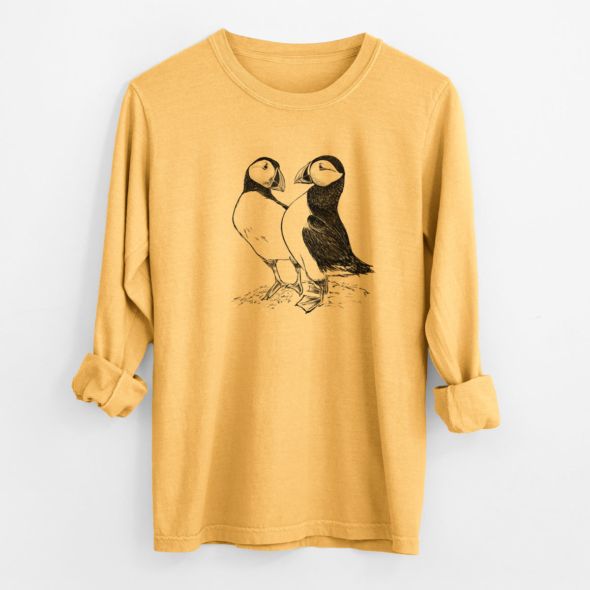 Golden wheat yellow Comfort Colors long sleeve shirt laid flat with the cuffs rolled, printed with a detailed black ink illustration of two Atlantic puffins standing side by side.