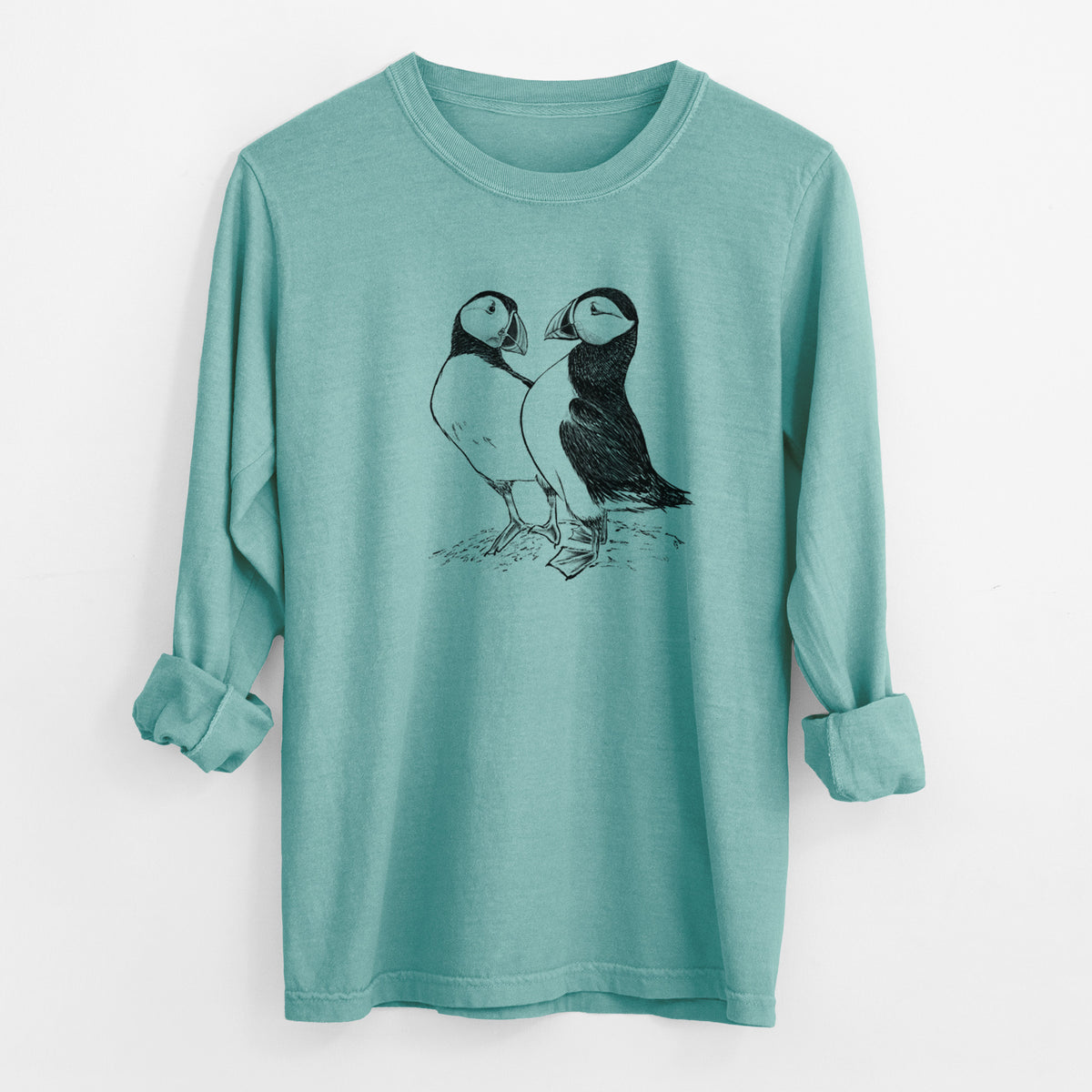 Reef green Comfort Colors long sleeve shirt laid flat with the cuffs rolled, printed with a detailed black ink illustration of two Atlantic puffins standing side by side.