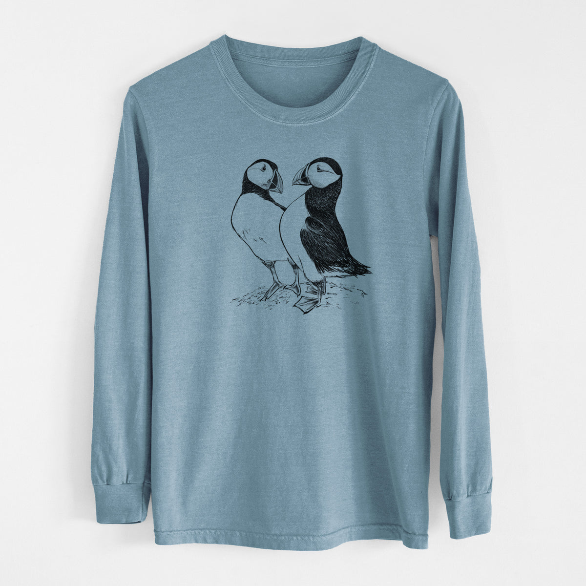 Steel blue Comfort Colors long sleeve shirt laid flat, printed with a detailed black ink illustration of two Atlantic puffins standing side by side.