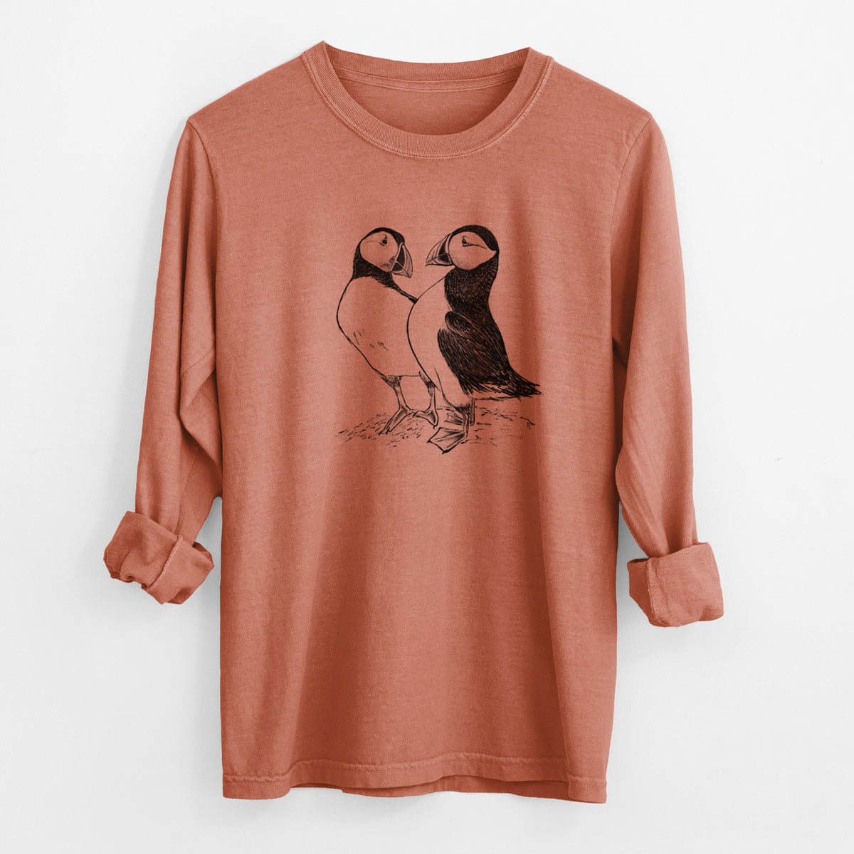 Yam burnt orange Comfort Colors long sleeve shirt laid flat with the cuffs rolled, printed with a detailed black ink illustration of two Atlantic puffins standing side by side.