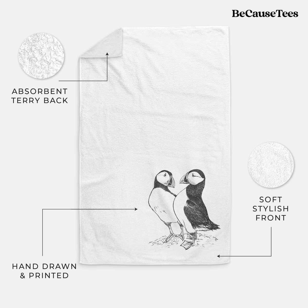 White hand towel printed with a detailed black ink illustration of two Atlantic puffins standing side by side.