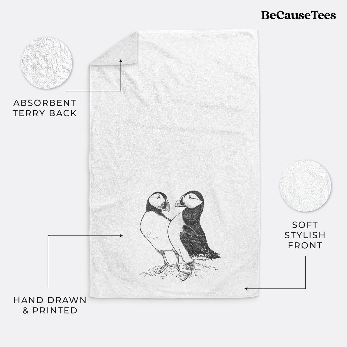 White hand towel printed with a detailed black ink illustration of two Atlantic puffins standing side by side.
