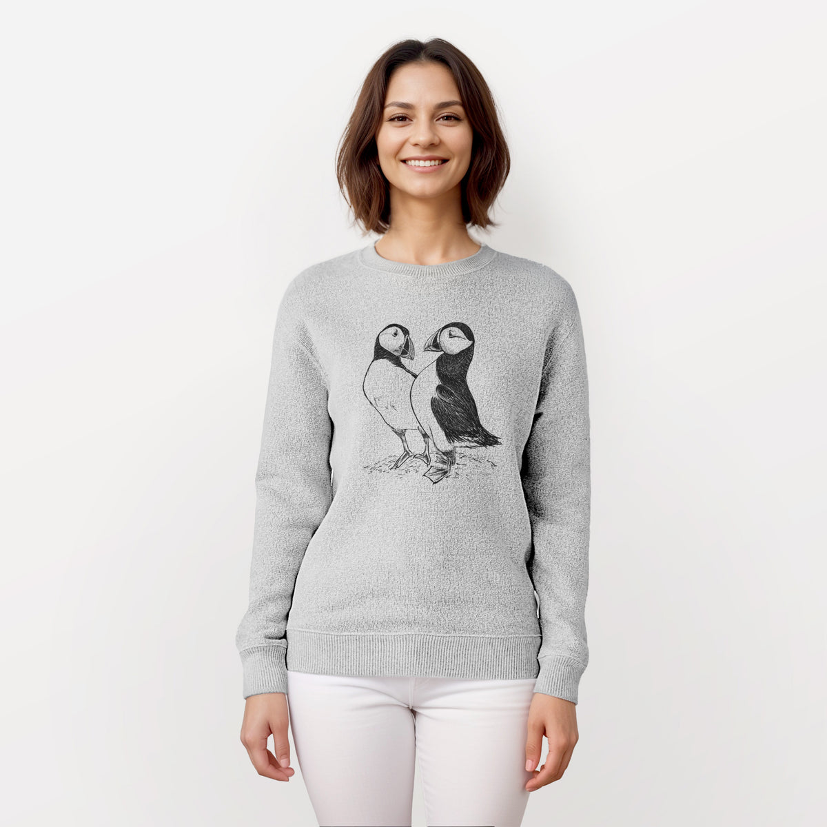Woman wearing a knit sweatshirt printed with a detailed black ink illustration of two Atlantic puffins standing side by side.