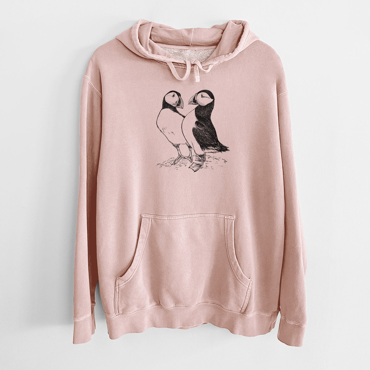 Dusty pink pigment dyed hoodie laid flat, printed with a detailed black ink illustration of two Atlantic puffins standing side by side.