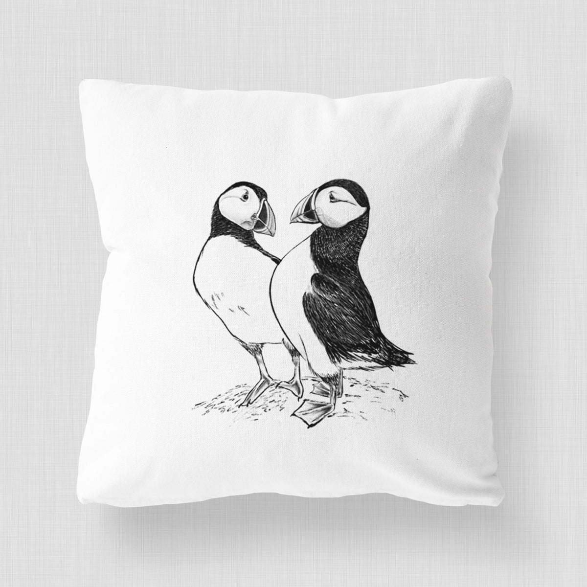 White pillow cover printed with a detailed black ink illustration of two Atlantic puffins standing side by side.