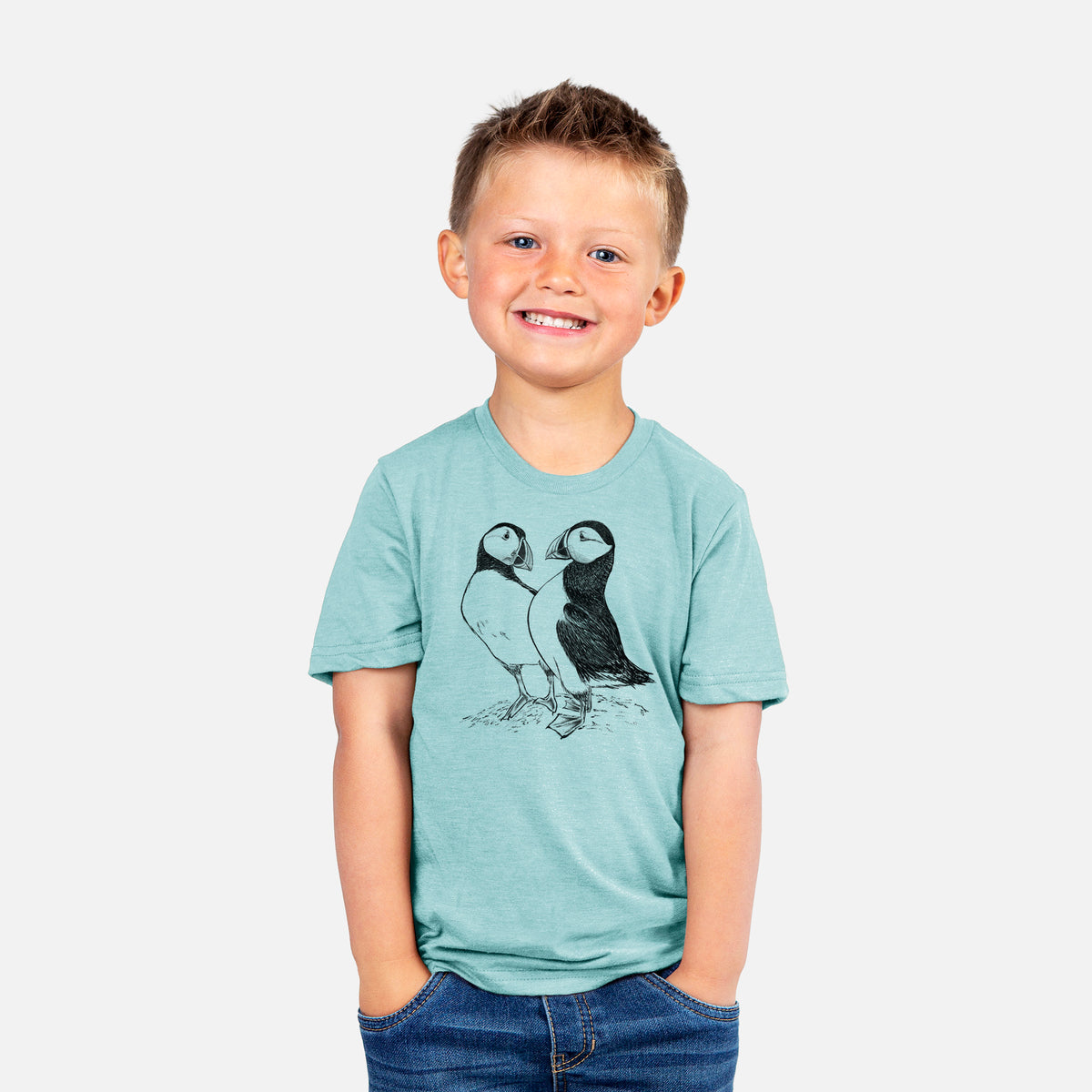 Smiling boy wearing a youth t-shirt printed with a detailed black ink illustration of two Atlantic puffins standing side by side.
