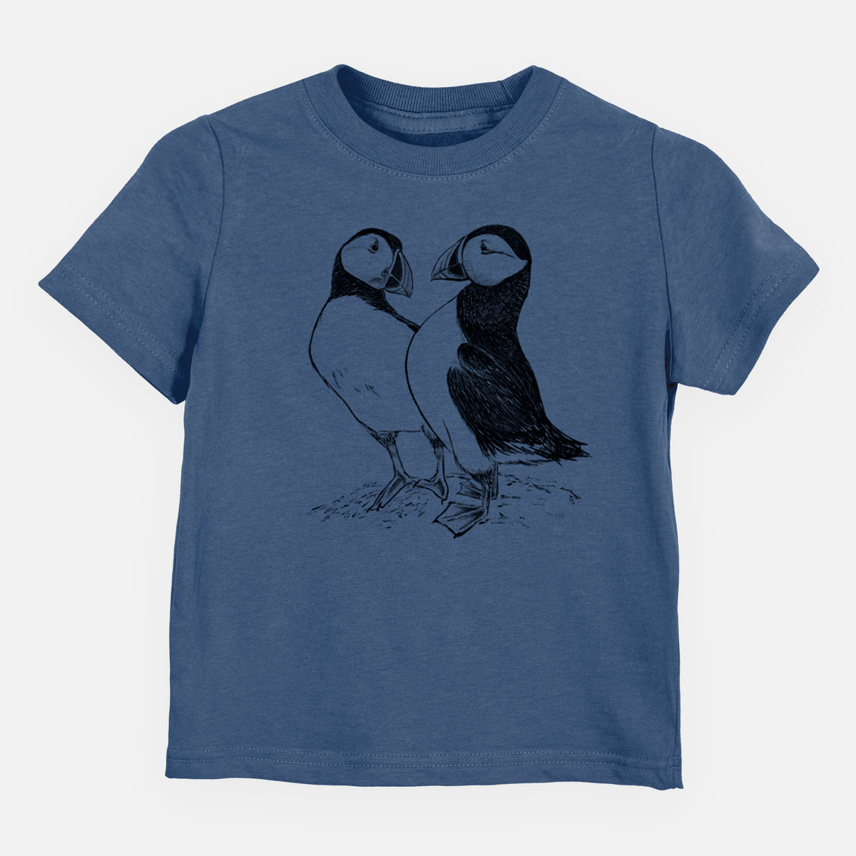 Indigo blue toddler t-shirt laid flat, printed with a detailed black ink illustration of two Atlantic puffins standing side by side.
