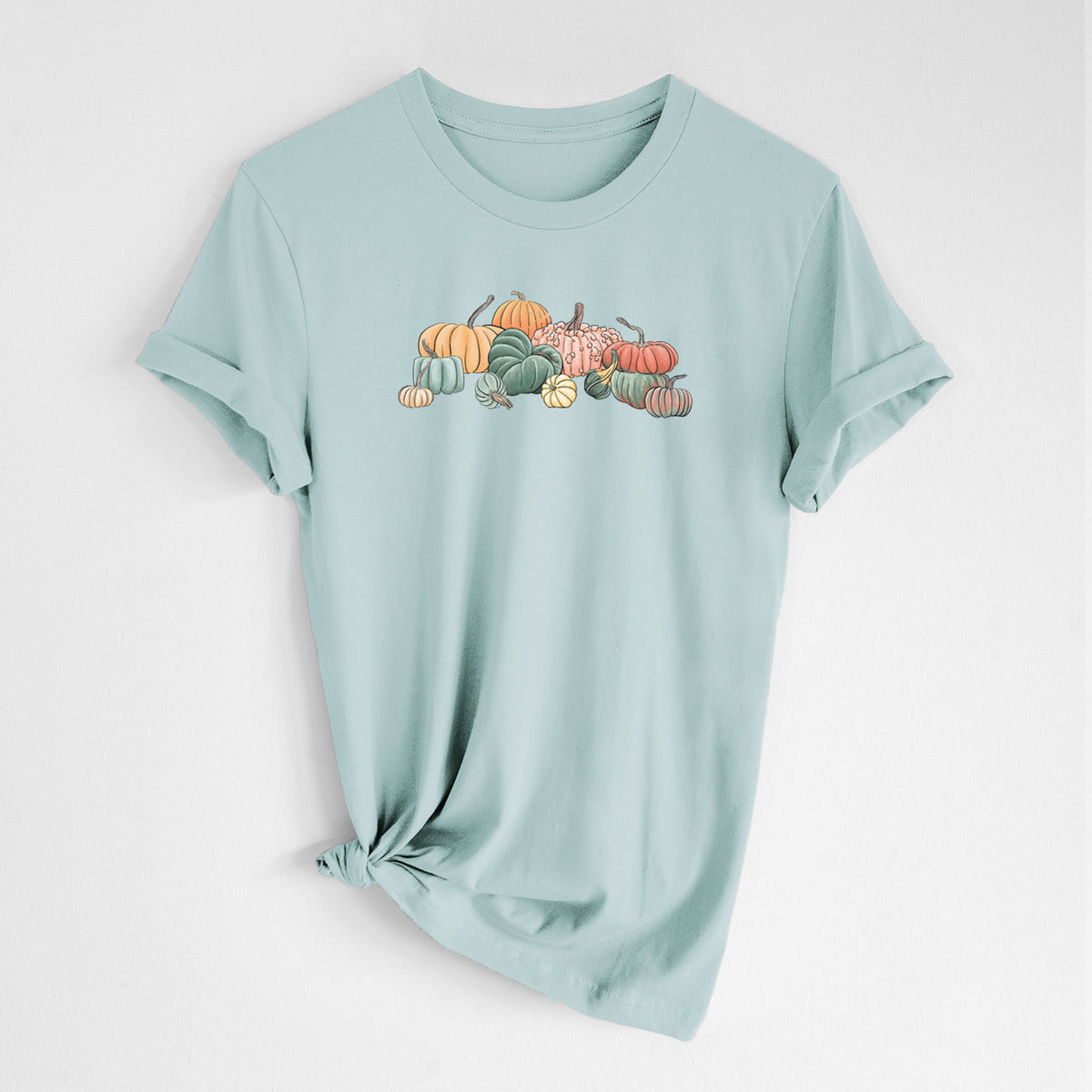 Dusty blue lightweight cotton t-shirt laid flat with the sleeves rolled, printed with a full-color illustration of a pile of pumpkins and gourds in orange, green and white.